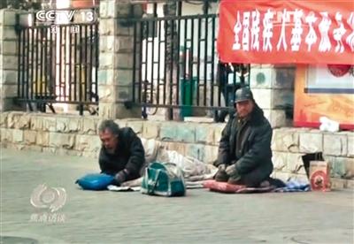 工人體育場(chǎng)北路，兩位乞討者路邊乞討，并輪流扮成“病人”（躺地者）。 央視截圖