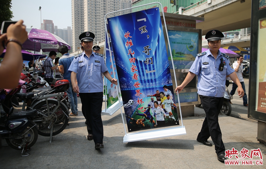7月2日上午，鄭州市紫荊山地鐵站出入口，執(zhí)法人員抬著寫有勸導(dǎo)語的宣傳板，前往占道經(jīng)營攤位“圍觀執(zhí)法”