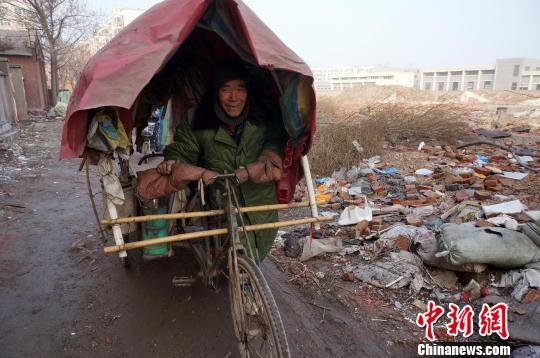圖為老人走出窩棚，推著三輪車準(zhǔn)備出去撿拾廢品。周小云 攝